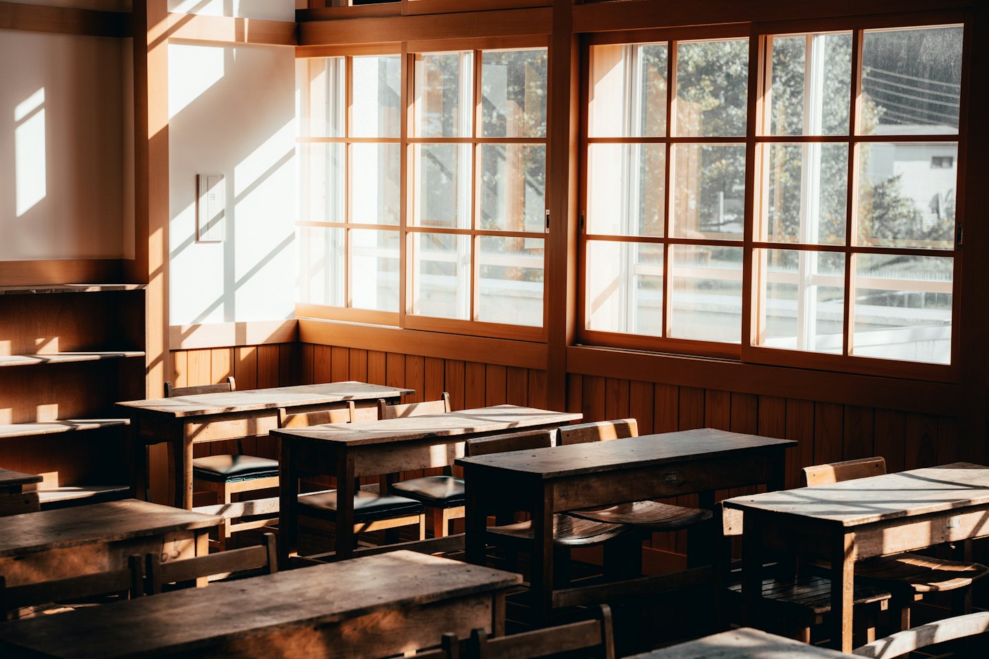 La luce del sole entra in un'aula vuota con banchi di legno.