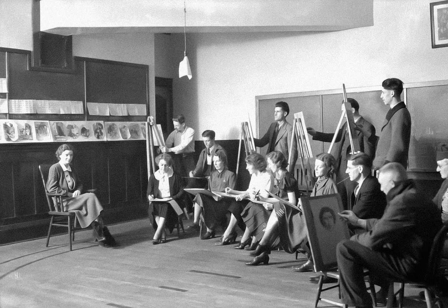 Studenti dipingono e disegnano a cavalletti in uno studio d'arte.