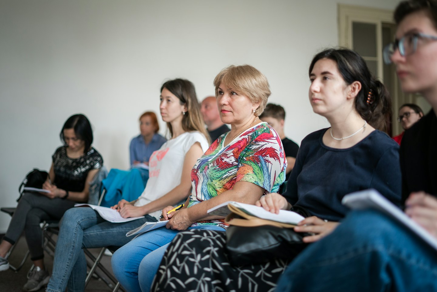 Adulti che partecipano a una lezione e prendono appunti.